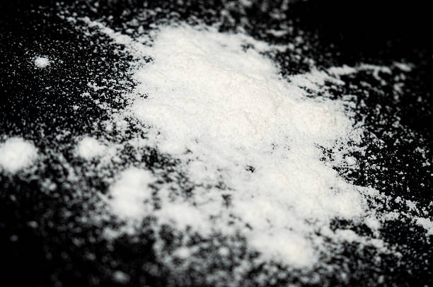 A quantity of fine white powder is scattered across a black background.