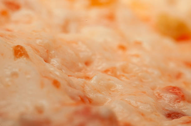 Melting cheese flows over a pizza base, showing a close-up texture of the mozzarella.