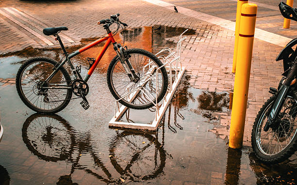 istock a bicycle leaning against a bike rack on a wet surface, with a reflection visible in the water after the rain 2211651427