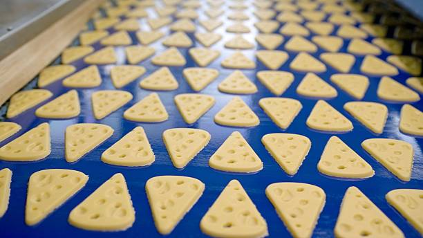 istock Cheese crackers moving on conveyor belt in food processing plant 2211655796