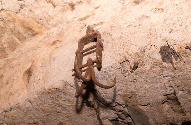 Ancient rusty metal hanger on stone wall in historic cave setting, lifestyle
