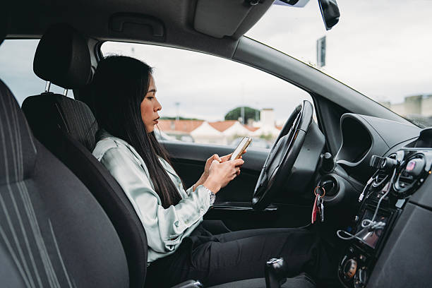 istock Businesswoman texting on phone while driving her car 2211658555