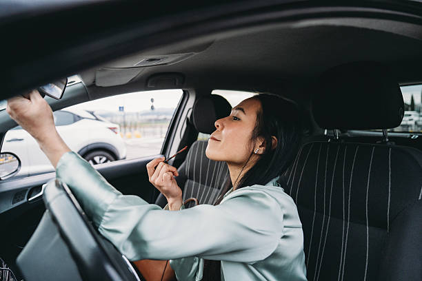 istock Businesswoman applying lipstick while driving her car 2211658581
