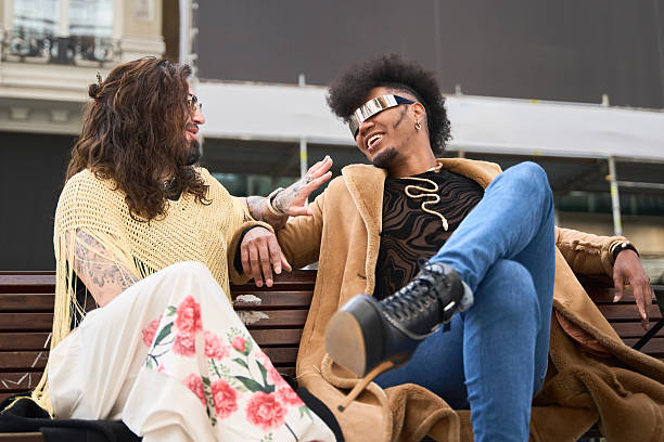 istock Gay couple smiling and talking on a bench 2211658593