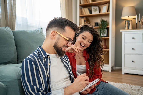 istock Young couple laughing and writing notes at home 2211664404