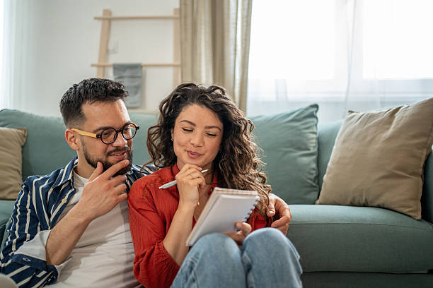 Young couple sitting on floor taking notes and planning finances