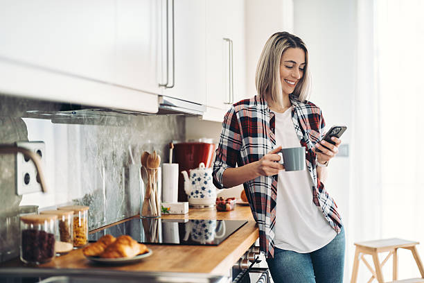istock Young woman checking her phone while having her morning coffee 2211664835