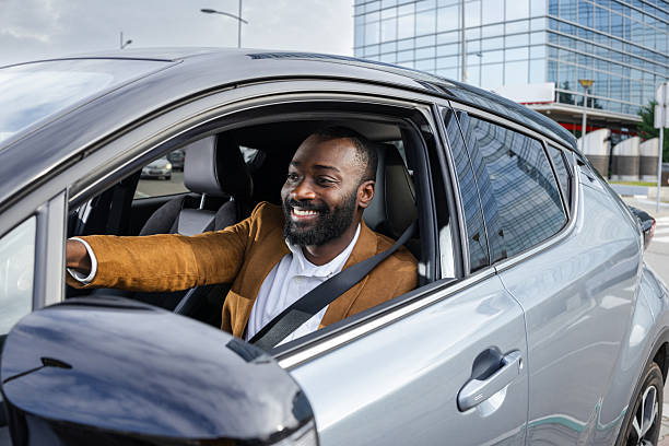 istock Man driving a car with a cheerful expression in an urban environment 2211668100