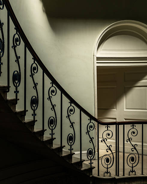 A top-down view of a modern spiral staircase with curved marble steps and glass railings.