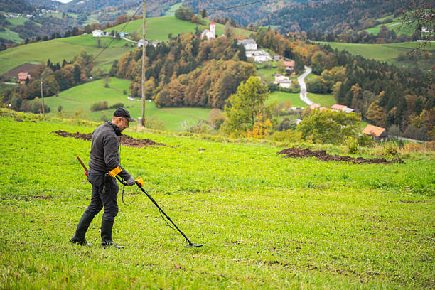 istock Man Using Metal Detector in Scenic Countryside 2211669363