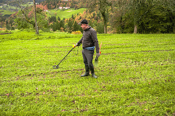 istock Man Using Metal Detector in Grassy Field 2211669383