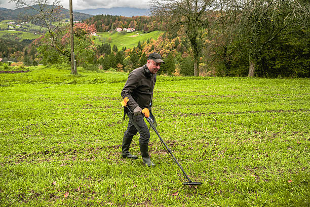istock Man Using Metal Detector in Grassy Field 2211669384
