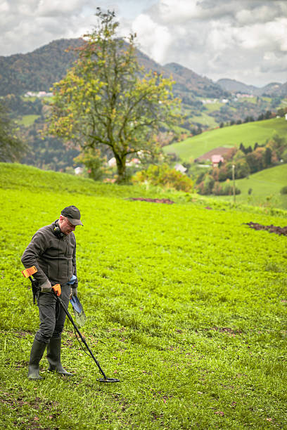 istock Man Using Metal Detector in Scenic Countryside 2211669408