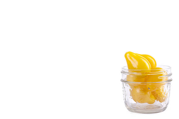 Yellow Pearshaped cherry tomatoes in a jar on white background.