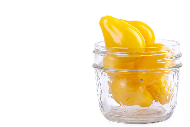 Yellow Pearshaped cherry tomatoes in a jar on white background.