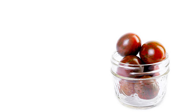 Cherry tomatoes "Chocolate sprinkles" in a jar on white background.