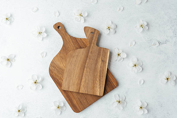 istock Wooden cutting boards arranged with delicate white flowers on a light background 2211676886