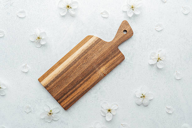 istock Beautiful wooden cutting board on a light surface adorned with white flowers 2211676891