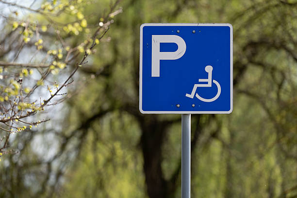 istock Handicapped parking sign with green foliage background 2211677247