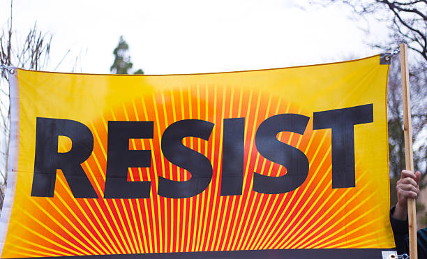 istock Hand Holding Large Yellow/Orange Protest Banner: RESIST 2211677424