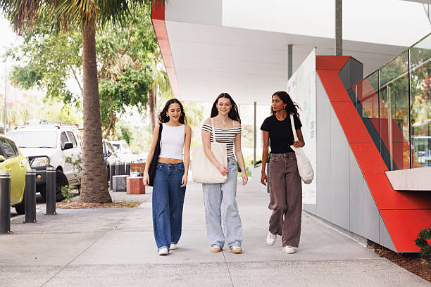 istock Diverse group of three teenage students walking across campus 2211679851