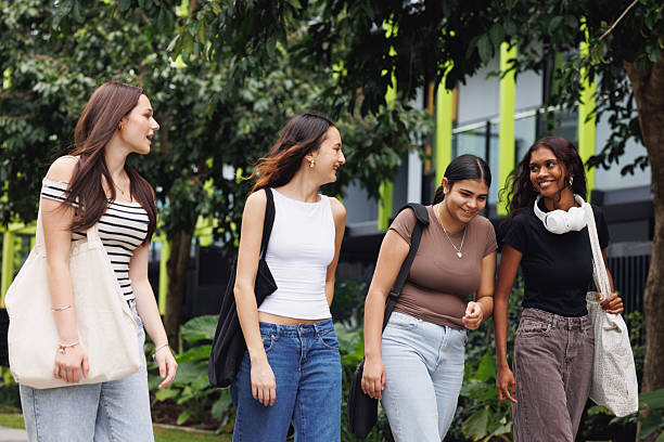 istock Diverse group of four university students walking through campus grounds 2211680586