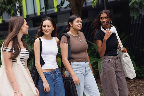 istock Diverse group of four university students walking through campus grounds 2211680587