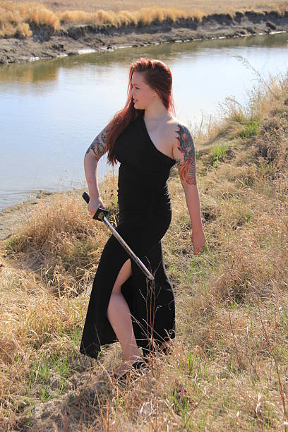 The beautiful redheaded model CJ practices with her sword on the river.
