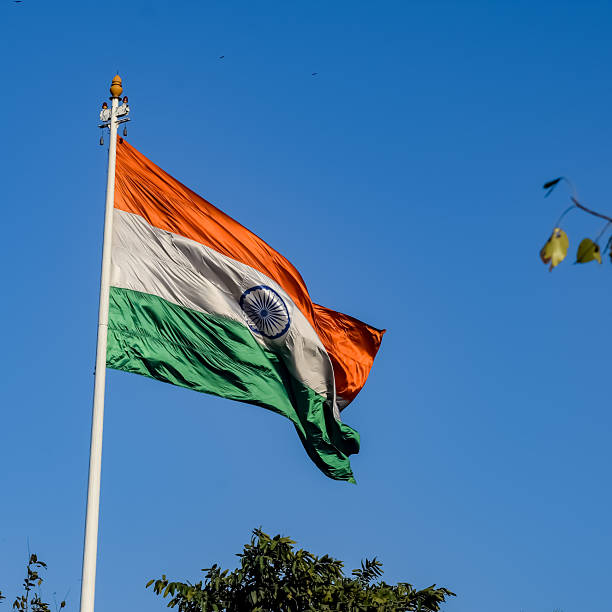 istock India flag flying high at Connaught Place with pride with plain white background, India flag fluttering, Indian Flag on Independence Day and Republic Day of India, tilt up shot, Har Ghar Tiranga 2211693514