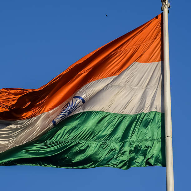 istock India flag flying high at Connaught Place with pride with plain white background, India flag fluttering, Indian Flag on Independence Day and Republic Day of India, tilt up shot, Har Ghar Tiranga 2211693574