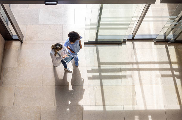 High angle view of a doctor looking at test results with a nurse on a digital tablet while walking at the hospital