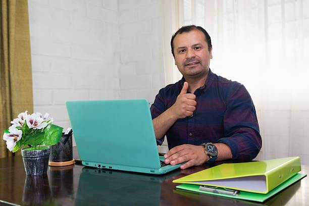 istock man sitting at his desk making a positive gesture with his finger 2211703586