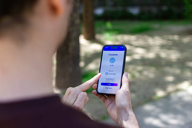 istock Young adult completing mobile payment in public park 2211704663