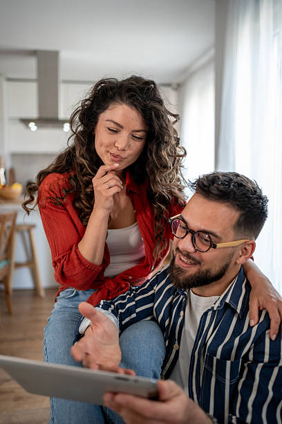istock Young couple relaxing at home browsing internet on digital tablet 2211706903