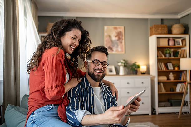 istock Happy couple relaxing at home, browsing internet on tablet 2211706970