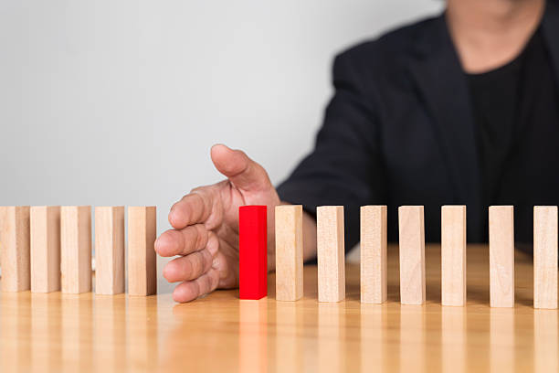 istock Businessman Stop Domino Effect. Risk Management and Insurance Concept. 2211711069