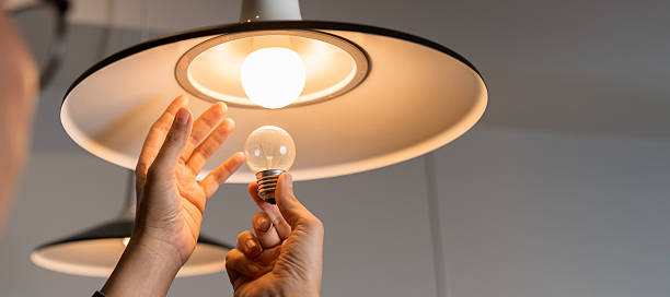 istock Male hands compare an incandescent light bulb and a LED lamp. 2211711072