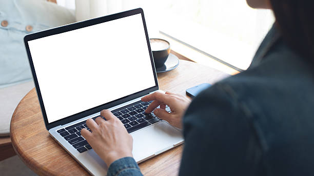 istock Laptop computer blank screen mockup. Woman working on laptop with empty screen for advertising, contact business search information on desk at coffee shop. marketing and web design template 2211713488