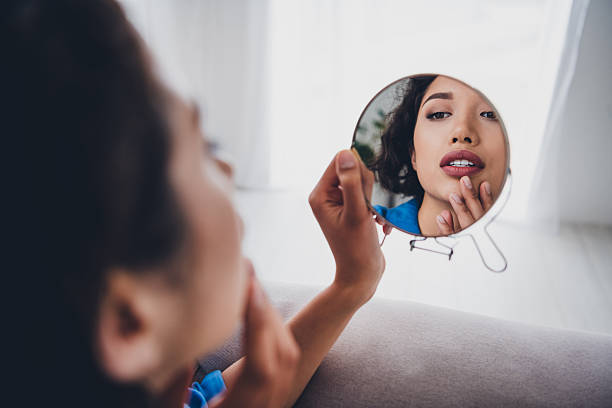 istock Young woman exploring her reflection in a mirror while relaxing at home on a calm day enjoying a serene and domestic atmosphere indoors 2211716093