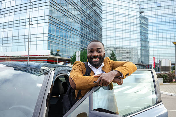 istock Confident man standing by car outdoors in modern urban setting 2211717126