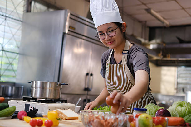 istock Chef picking fresh brown eggs from a glass bowl in a kitchen filled with colorful produce 2211717304