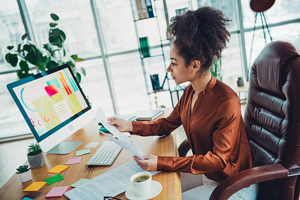 istock Young professional businesswoman analyzes documents in a stylish loft office interior while working on a desktop computer 2211717414