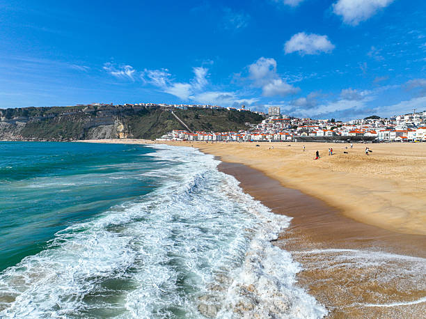 istock Shoreline wave rolling into beach at Nazare 2211718262