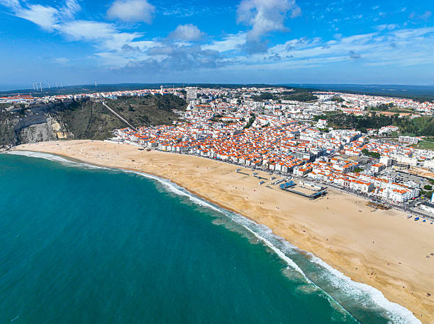 istock Ocean wave along Nazare coast and hillside town 2211718603