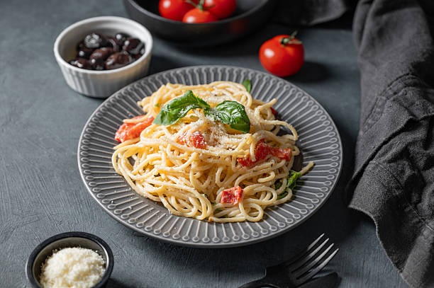 istock Creamy spaghetti with cherry tomatoes, parmesan cheese and basil on a plate on a dark background 2211718756
