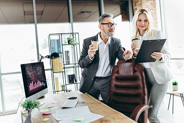 istock Professional coworkers reviewing a document together in a modern office setting, discussing business strategies and enjoying coffee 2211719724