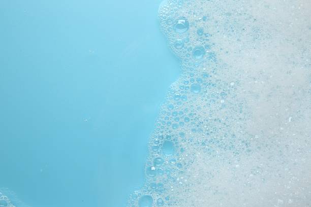 istock Washing laundry. White foam with bubbles on light blue background, top view. Space for text 2211723285