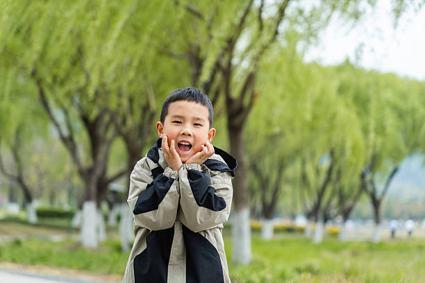 Close up of smiling Asian girl in the garden. Portrait of kid side view.
