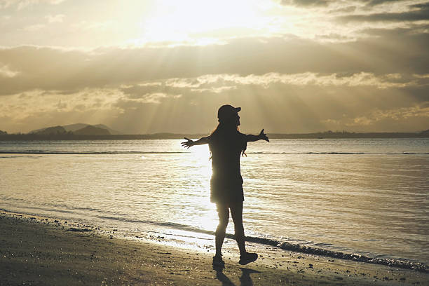 istock Silhouette of a woman open arms while strolling on the beach 2211724040