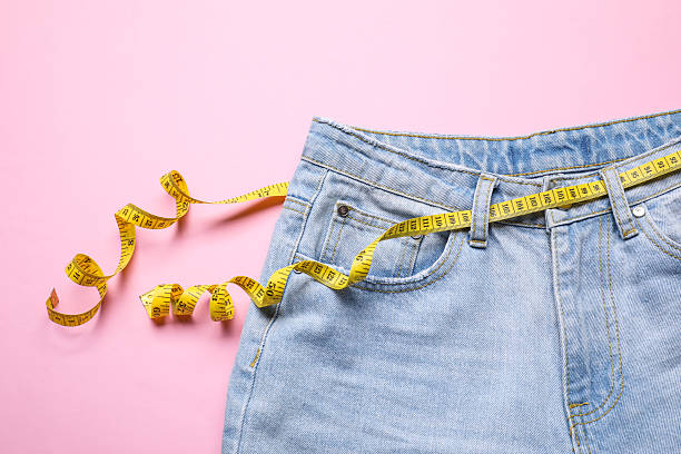 istock Jeans and measuring tape on pink background, top view 2211724427